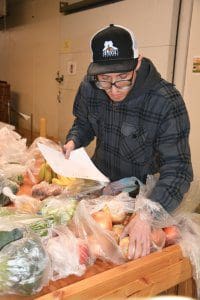  Kevin Roberts, volunteer with EmployAbility, package NLaws at Home food items for St. Joseph's / Candler orders.